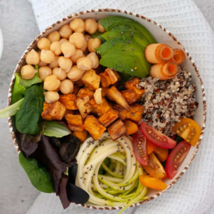 Vibrant Buddha Bowl: A colorful array of fresh, nutrient-packed ingredients in a bowl. A medley of quinoa, roasted sweet potatoes, avocado slices, cherry tomatoes, sautéed kale, and chickpeas. Drizzled with a tahini dressing for a delicious and wholesome plant-based meal.
